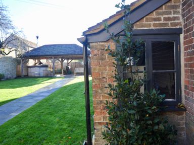 A garden with a brick wall and pathway at ASH HOUSE in Wincanton