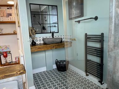 A bathroom with a sink, mirror, and towel radiator in a modern design at The Old Barn in Manchester