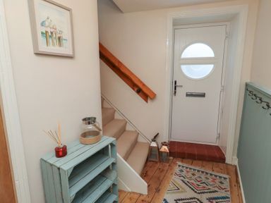 A hallway with a staircase and door at Corner Cottage in Seahouses