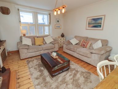 A living room with two sofas, a coffee table and a lamp at Corner Cottage in Seahouses