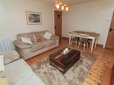 A living room with a sofa and dining table at Corner Cottage in Seahouses