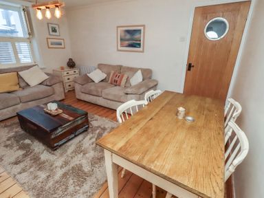 A living room with a dining table and sofas at Corner Cottage in Seahouses