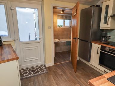 A kitchen with a door and access to bathroom at Corner Cottage in Seahouses