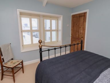 A bedroom with a bed and window at Corner Cottage in Seahouses