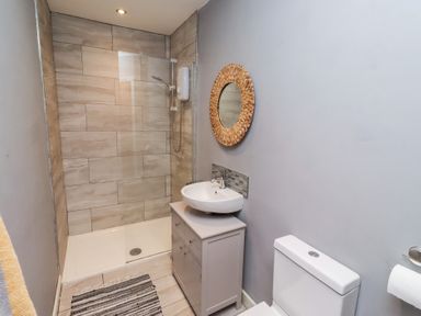 A bathroom with a shower, sink, and toilet at Corner Cottage in Seahouses