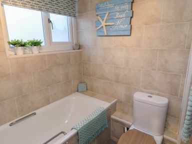 A bathroom with bathtub and toilet at Corner Cottage in Seahouses