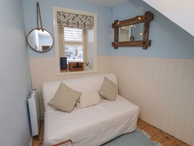 A snug with a sofa and a mirror at Corner Cottage Seahouses