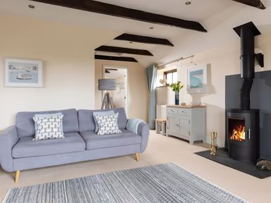 A living room with a sofa and fireplace at The Granary, Engollan near St Merryn