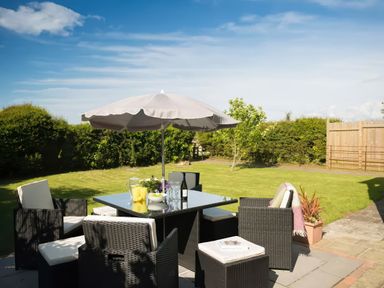 A garden with a table and chairs under an umbrella at The Granary near St Merryn