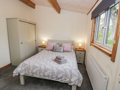 A bedroom with a bed and wardrobe at Willow Lodge in Admaston near Abbots Bromley
