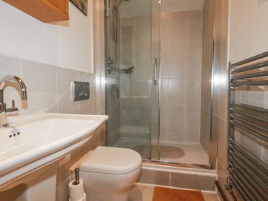 A bathroom with a shower, sink and toilet at Blowing House Cottage in Perranporth