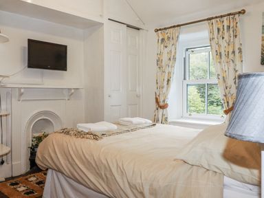 A bedroom with a television and a bed at Blowing House Cottage in Perranporth