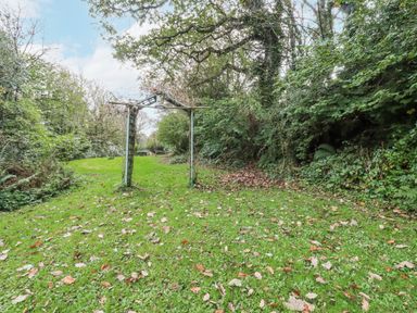 A garden with an archway and fallen leaves at Blowing House Cottage Perranporth