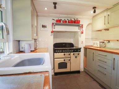 A kitchen with a cooker and microwave at Blowing House Cottage near Perranporth