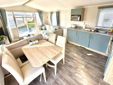 A living room with sofa and dining area at a holiday home in an outdoor setting