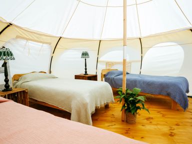 A tent interior with beds and lamps at 