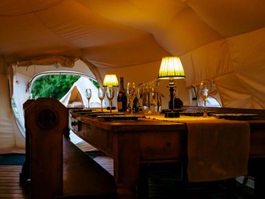 A dining room with a table set at a glamping site in a tent