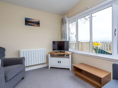A living room with a TV and armchair at Kilninver Chalet