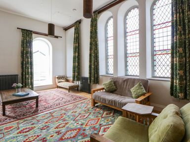 A living room with a table and sofas at Capel Llani Llanidloes