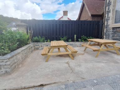 An outdoor area with wooden tables and plants at Capel Llani Llanidloes