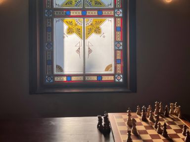 A chessboard with pieces and a stained glass window at Capel Llani in Llanidloes