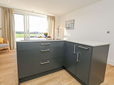 A kitchen with a dark island and a window at Sea Fern House - 36 in Poole