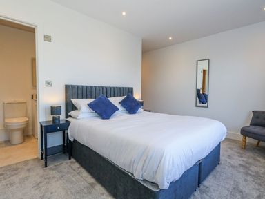 A bedroom with a bed, lamp, and mirror at Sea Fern House - 36 in Poole