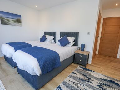 A bedroom with twin beds and a nightstand at Sea Fern House - 36 Poole