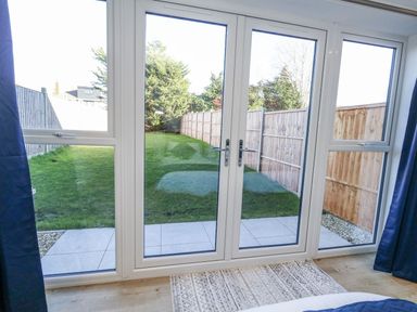 A bedroom with double doors leading to a garden at Sea Fern House - 36 Poole