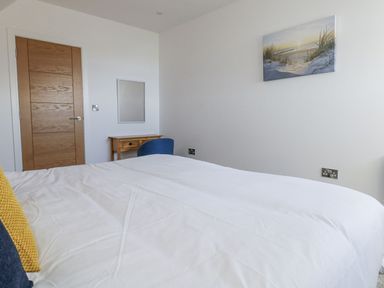 A bedroom with a bed, chair, and wall art at Sea Fern House - 36 Poole