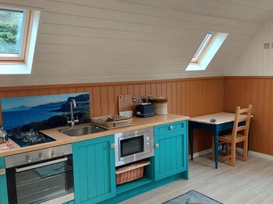 A kitchen with a stove, sink, microwave, and table at The Old Barn in Manchester