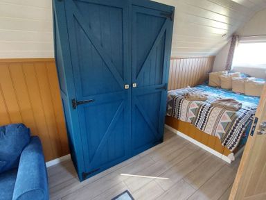 A bedroom with a blue wardrobe and a bed at an unspecified location