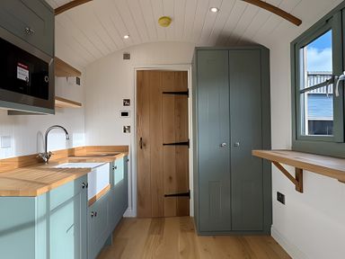 A kitchen with a sink, microwave, and cabinet at Y Nyth
