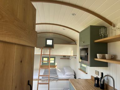 A sleeping area with a bed and kitchenette at Y Nyth 