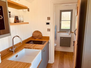 A kitchen with sink and stove leading to a bathroom at Y Nyth