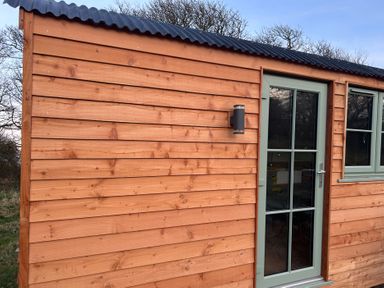 A wooden cabin exterior with a door and window at Y Nyth