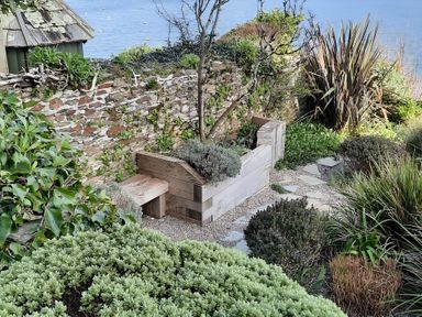 A garden with a stone wall and garden bed at Lil Nauti