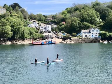 Paddle boarders on water with houses and trees in the background at Lil Nauti