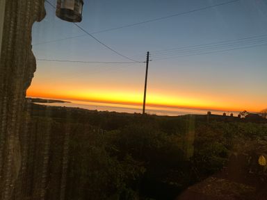 A sunset view overlooking water and landscape at Bwthyn Nain 