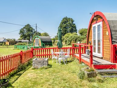 A garden with glamping pods and outdoor seating at St Austell Glamping St Austell