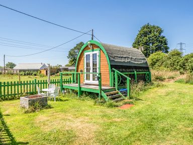A wooden cabin with steps and a green fence at St Austell Glamping in St Austell