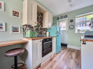 A kitchen with a fridge, oven, and bar stool at 20 Main Street in Heysham