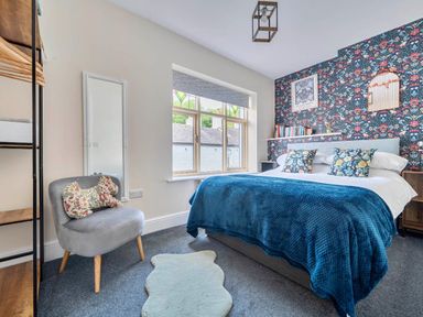 A bedroom with a bed, chair, and window at 20 Main Street in Heysham
