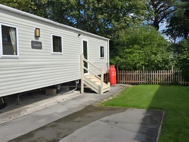 An outdoor area with a caravan and a lawn at Caravan