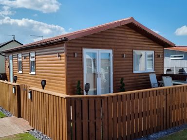 A wooden cabin with a fence and door at 50 Bridlington