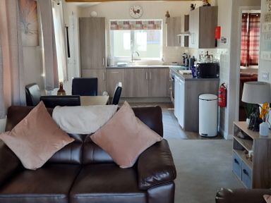 A living room with a sofa and kitchen area at 50 Bridlington