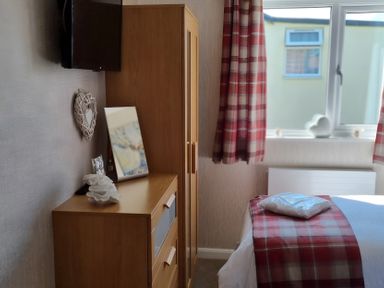 A bedroom with furniture including a wardrobe, chest of drawers, and a television at 50 Bridlington