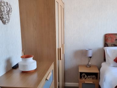 A bedroom with a wardrobe, lamp, side table, and vase at 50 Bridlington