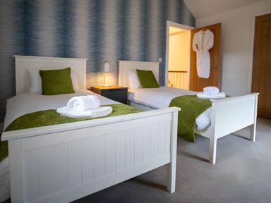 A bedroom with two beds, a nightstand, and a robe at The Galloway in Morpeth