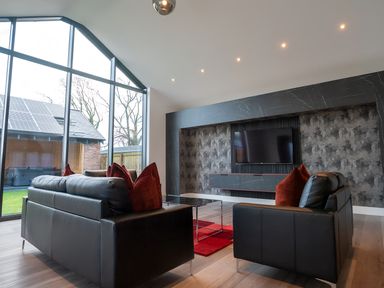 A living room with a black sofa and television at The Shearling in Morpeth